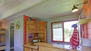 A rustic kitchen with wooden cabinets, a wooden counter, a window with a view, and a unique fish decoration. - Charming caravan for 4 guests with pets allowed, linens and cleaning included (Saint-Germain-Lespinasse)
