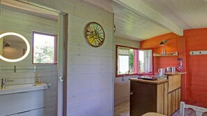 A cabin interior with a wooden interior, a bathroom with a sink and mirror, a wooden table, and a clock on the wall. - Charming caravan for 4 guests with pets allowed, linens and cleaning included (Saint-Germain-Lespinasse)