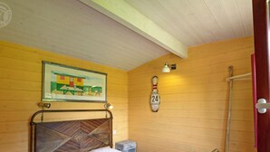 A single bed with a wooden headboard, a small bedside table, a wall clock, and a framed picture on the wall. - Charming caravan for 4 guests with pets allowed, linens and cleaning included (Saint-Germain-Lespinasse)