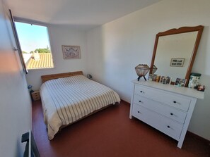 Una camera da letto con un letto, una cassettiera, uno specchio e una finestra.