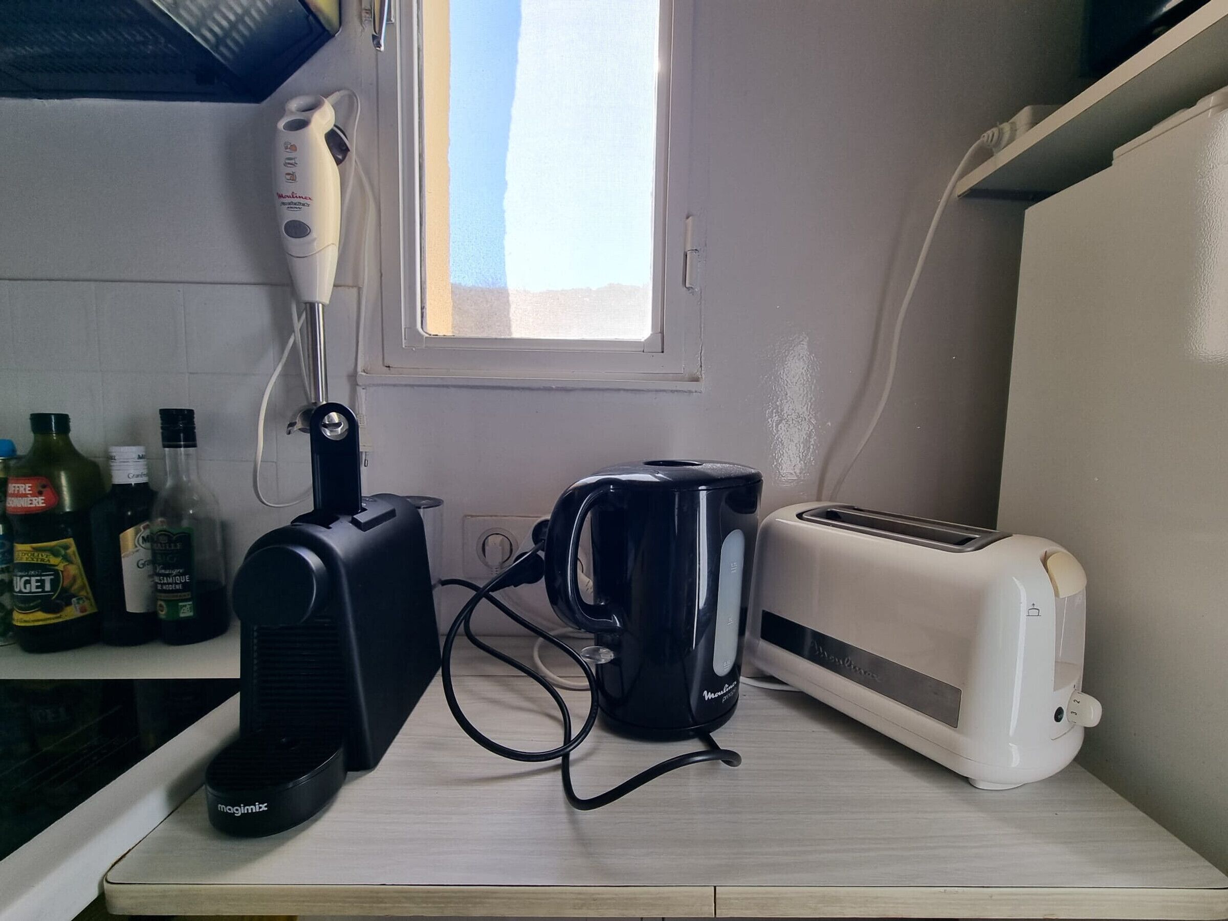 A kitchen with a toaster, a coffee maker, and a hairdryer on a countertop.