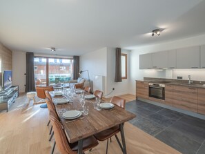Un appartement moderne comprenant un coin repas, une cuisine et un balcon aménagé avec du mobilier d’extérieur.