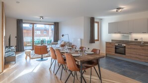 A modern kitchen with wooden cabinets, a built-in oven, and a dining area with a wooden table and chairs. - New apartment 108m², center Huez, parking, wifi, 6 guests (Huez)