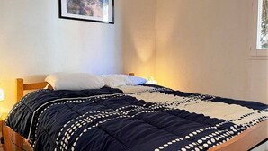 Une chambre à coucher avec un lit, des oreillers, une lampe de chevet et un tableau encadré au mur.