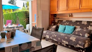 Une pièce confortable avec un canapé-lit, une table à manger avec des chaises et un coin cuisine doté de meubles en bois.