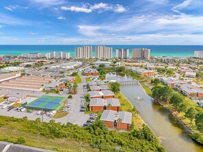 An aerial view of a coastal resort area with multiple buildings, a marina, and a river.