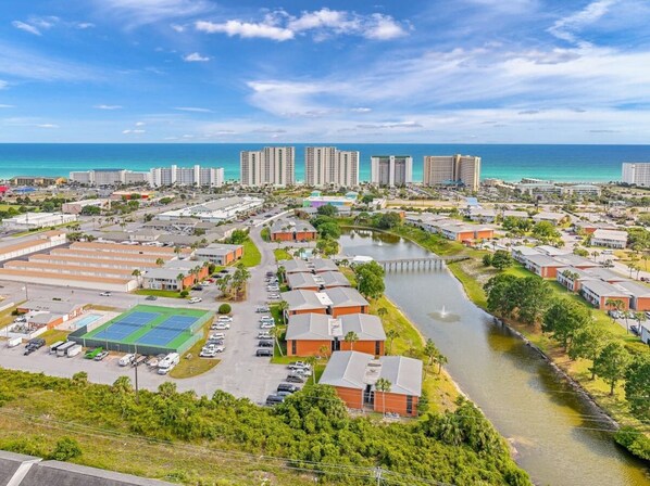 Vista aérea de una zona turística costera con varios edificios, un puerto deportivo y un río.