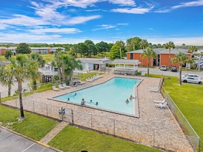 A swimming pool with a fenced deck, surrounded by palm trees and lounge chairs. - 2nd Floor King Bedroom w/Lagoon View (Destin)