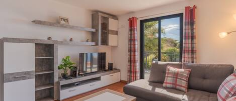 A modern living room with a sofa, TV, and storage units.
