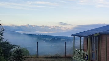 Une cabane offrant une vue sur un lac et, au loin, sur des montagnes.