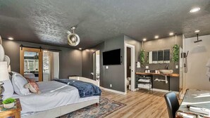 A modern bedroom with a large bed, a desk, and a television. - Spacious 4BR, Games, Pool, Theater & Private Yard! (Omaha)