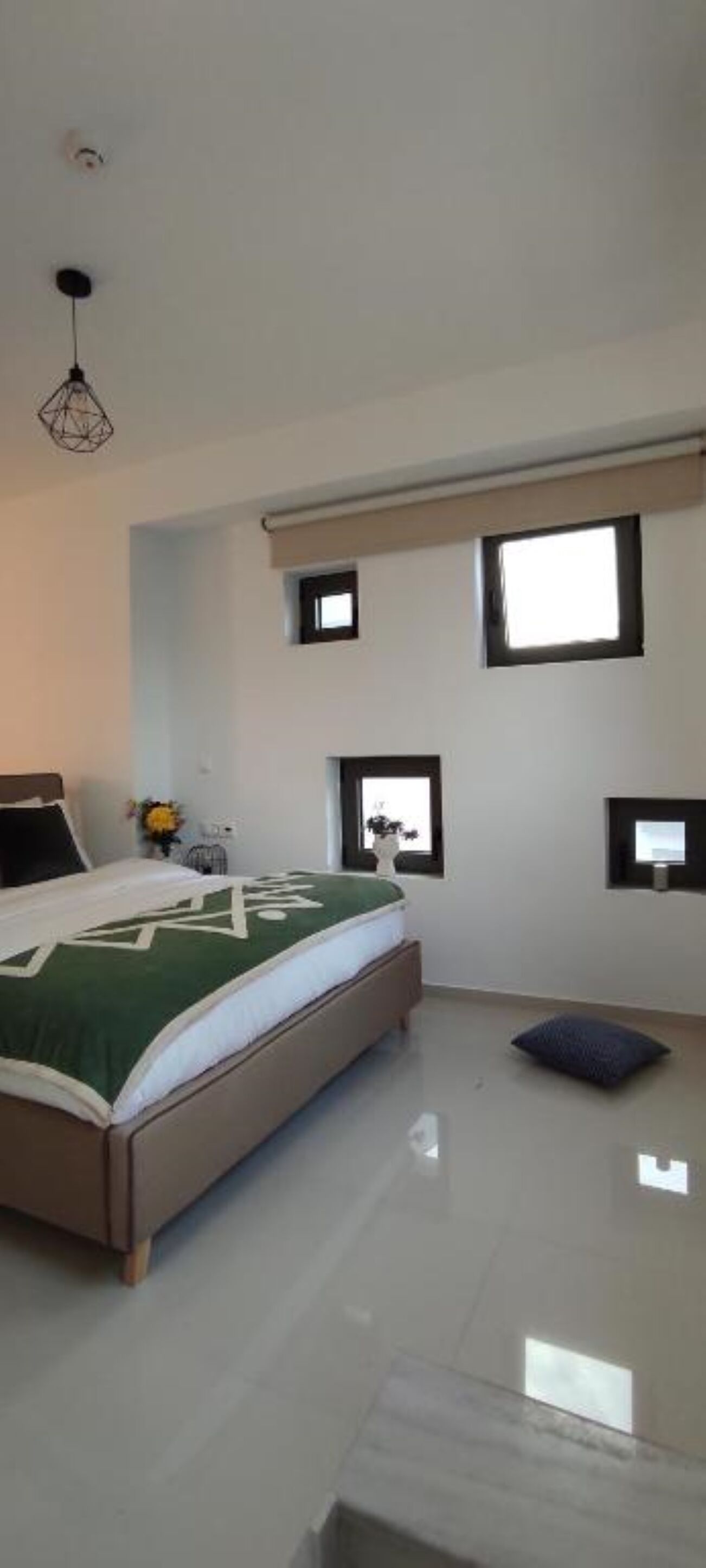 A bedroom with a bed, a small window, and a ceiling light fixture.