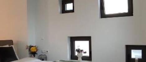 A bedroom with a bed, a small window, and a ceiling light fixture.