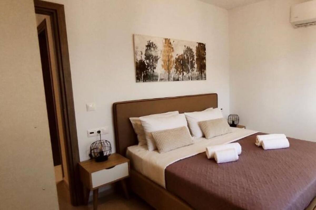Een slaapkamer met een bed, een nachtkastje, een schilderij en een airconditioning.