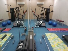 Un gimnasio con equipamiento de ejercicio, balones de ejercicio azules y un espejo grande.