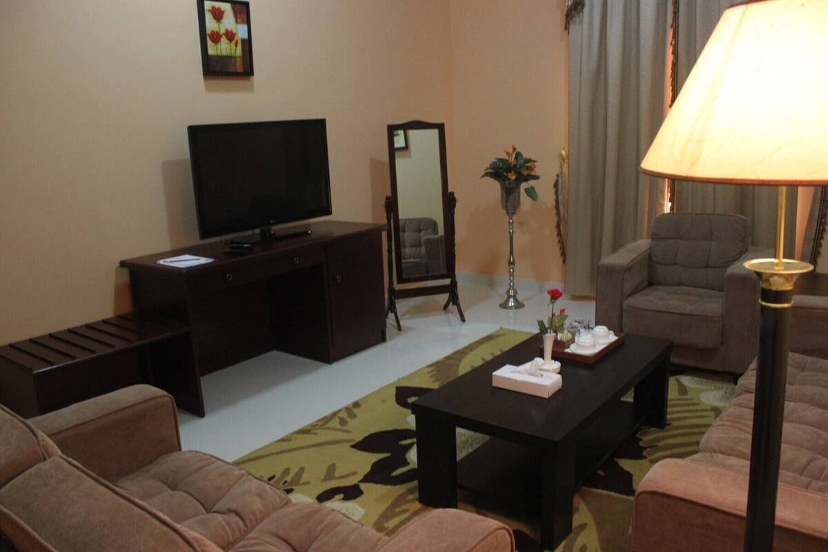 A living room with a television, sofa, coffee table, and lamp.