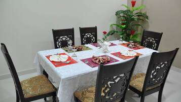 Una mesa de comedor vestida con mantel blanco, individuales rojos y un centro de mesa.