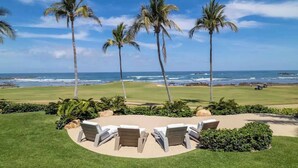 Um campo de golfe com palmeiras e vista para o oceano.