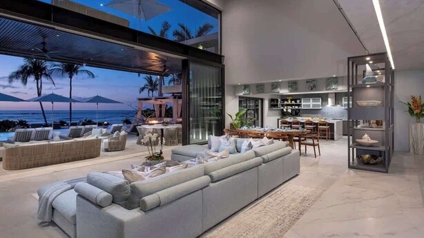 A modern living room with a large sofa, dining area, and kitchen.