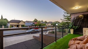 A balcony with a view of a residential street, a car parked on the street, and a potted plant. - Vintage Vibes East Freo 2B 1BA (East Fremantle)