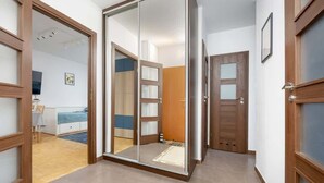 Un pasillo con una puerta corrediza de vidrio que da a un dormitorio con cama y escritorio.