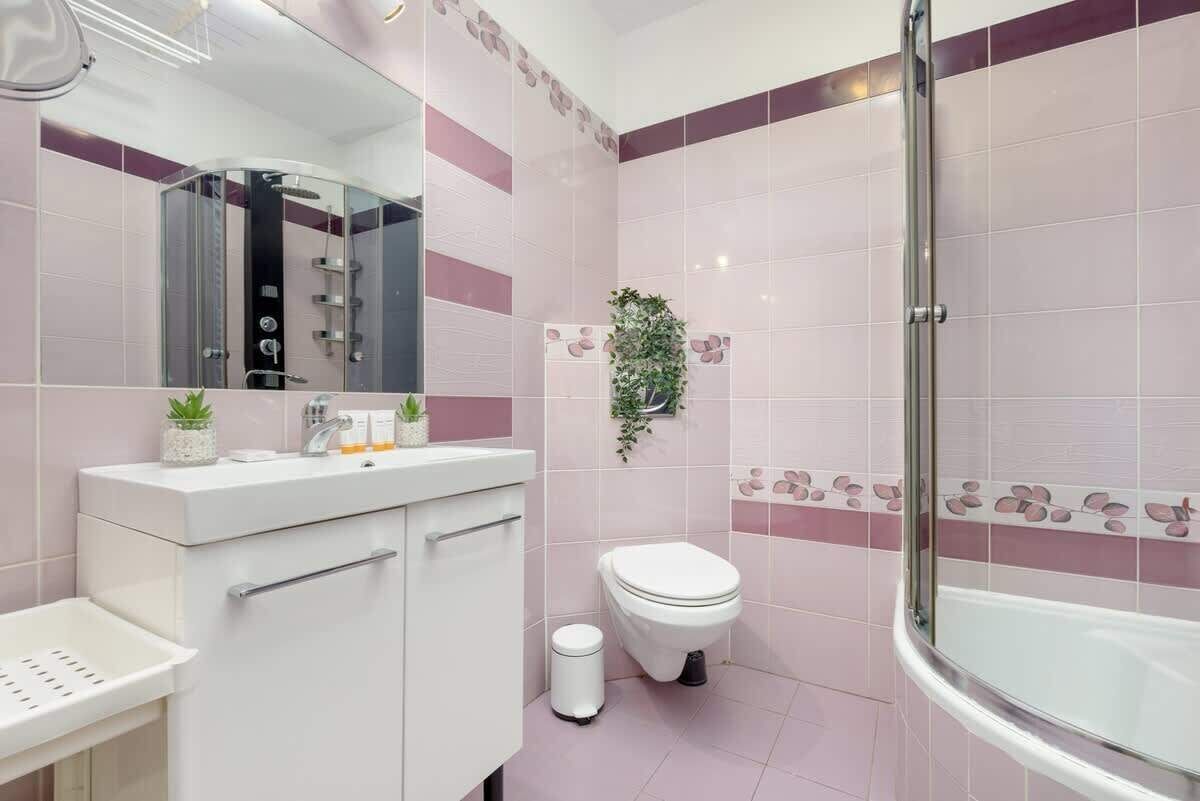 Une salle de bain moderne avec une douche à parois de verre, des toilettes blanches et un meuble-lavabo avec un évier et un miroir.