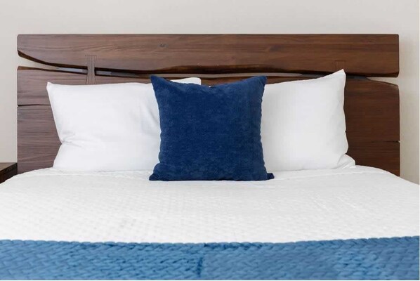 A bed with a wooden headboard, white and blue pillows, and a blue blanket. - Modern home near Six flags and Medical center (San Antonio)