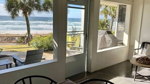 A room with a view of the ocean, a patio with outdoor furniture, and a stone sculpture.