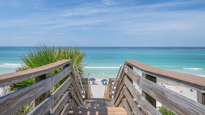 Un escalier en bois mène à une plage d’où l’on a une vue dégagée sur l’océan.