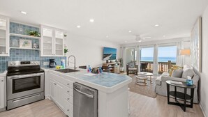 Une cuisine moderne dotée d’un îlot central, un coin repas avec vue et un salon comprenant un canapé et une table.