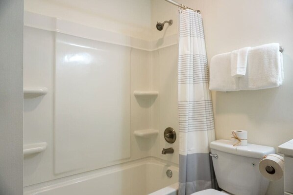 A bathroom with a shower, toilet, and towel rack.