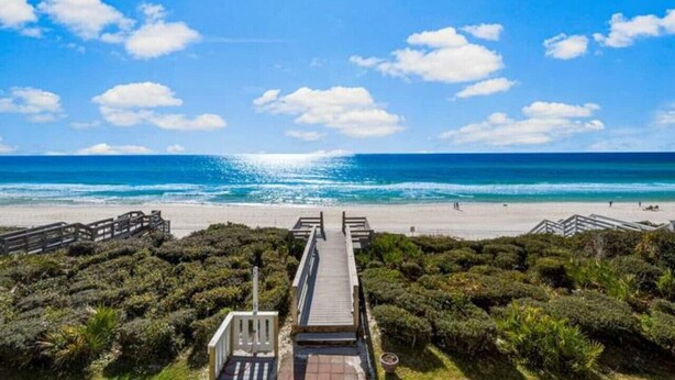 A beach with a wooden walkway leading to the shore, surrounded by dense greenery. - Seamist 7 ~ Beachfront on 30A (Seacrest)