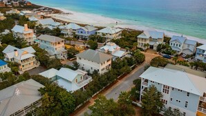 Un quartier résidentiel en bord de mer, avec des maisons situées à proximité de la plage, composé d’un mélange de bâtiments à un ou plusieurs étages, entouré de verdure et offrant une vue dégagée sur l’océan.