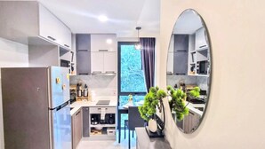 A modern kitchen with a refrigerator, stove, and sink, a large mirror, and a potted plant.