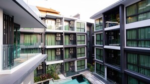 A multi-story building with balconies, large windows, and a central courtyard with a pool.