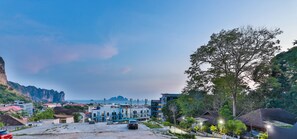 A coastal town with modern buildings, a large tree, and a view of the sea. - AO504 - 1 Bedroom Serviced Apartment Top Floor Forest View with Bathtub Ao Nang (Tambon Ao Nang)