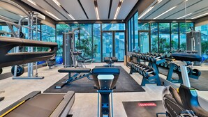 A modern gym with cardio equipment, weight machines, and dumbbells.