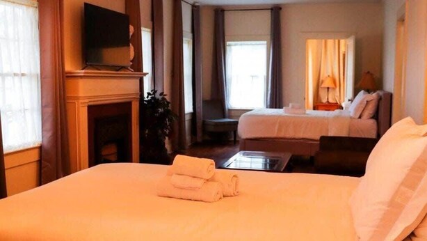 Una habitación de hotel con una cama grande, televisión sobre un mueble, escritorio y una silla.