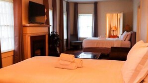 A hotel room with a large bed, a television on a stand, a desk, and a chair. - Spacious Corporate Lodging in Downtown Lafayette (Lafayette)