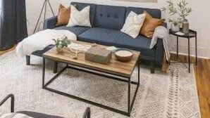 A living room with a blue sofa, a coffee table, a floor lamp, and a large abstract painting on the wall. - Spacious Corporate Lodging in Downtown Lafayette (Lafayette)