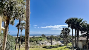 Vista di una proprietà costiera con palme, un edificio e una spiaggia sullo sfondo.