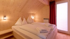 A wooden cabin room with a bed, pillows, and a window with curtains. - Murau 11 - large terrace & good location (Murau)