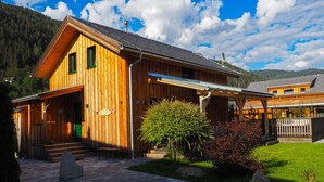 Un chalet de madera con un porche cubierto, una escalera de piedra y un jardín bien cuidado.