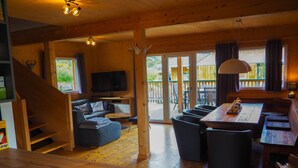 Un interior de madera con sofá, mesa de comedor y televisor.