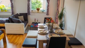 A dining area with a table set for four, a sofa, and a window with curtains. - Apartment Ottl 2 - charming and good location (St. Georgen am Kreischberg)