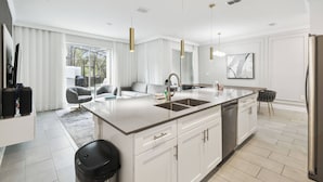 A modern kitchen with a large island, white cabinetry, and stainless steel appliances.