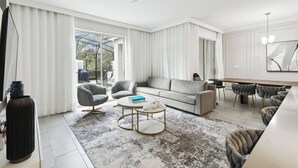 A modern living room with a sofa, armchairs, a coffee table, and a dining area with a table and chairs.