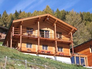 A wooden chalet with multiple balconies, large windows, and a sloped roof, surrounded by trees. - Beautiful, comfortable chalet for 8 people with a splendid view. Bright and spacious, on two floors, (St-Luc)