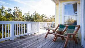 A wooden deck with two lounge chairs and a small table, overlooking a forested area. - 2min Walk to Beach, Pool, Spa, Game Room, Big Yard (Corolla)