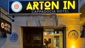 The exterior of the Arton Hotel, featuring a prominent entrance with a wooden door and illuminated signage. - Arton In Cappadocia (Avanos)